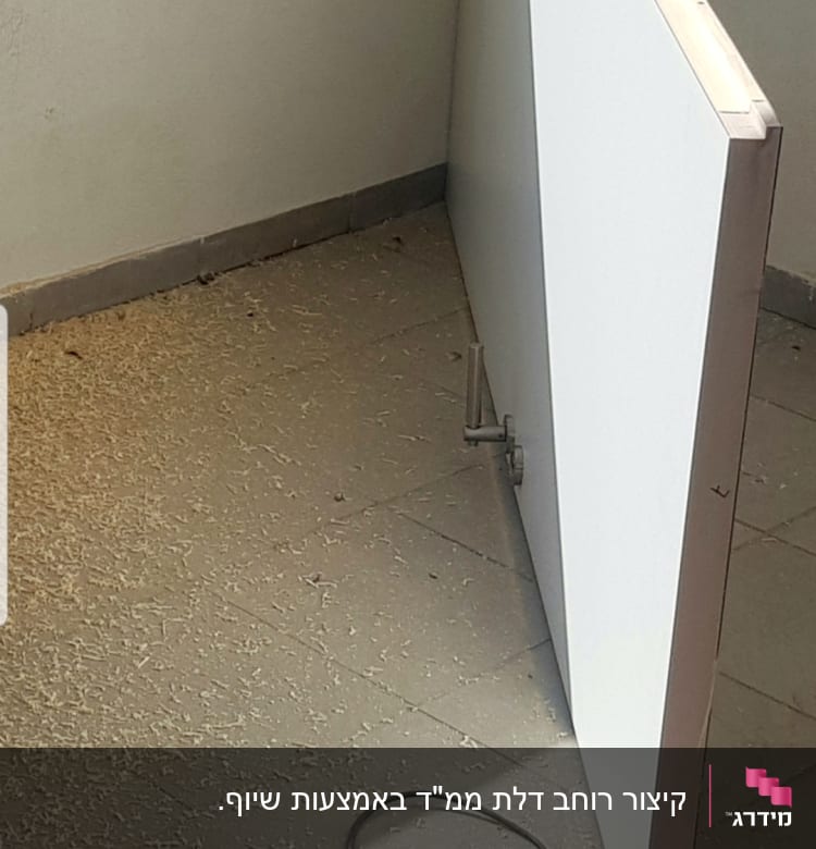 דלת לבנה מונחת על הרצפה עם צירים חשופים